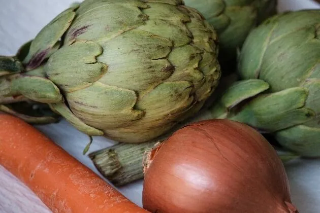 Carxofes brasejades al vi blanc amb vinagreta de pernil ibèric, rovell d'ou, ametlla i ceba cruixent