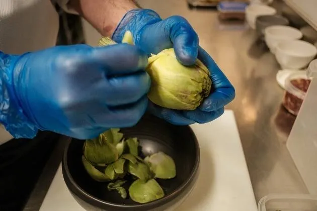 Carxofes brasejades al vi blanc amb vinagreta de pernil ibèric, rovell d'ou, ametlla i ceba cruixent
