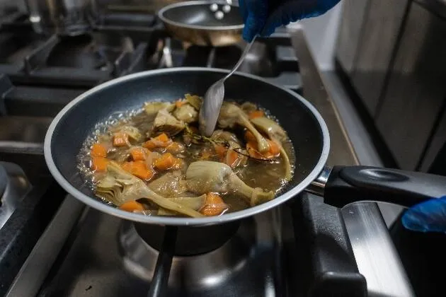 Carxofes brasejades al vi blanc amb vinagreta de pernil ibèric, rovell d'ou, ametlla i ceba cruixent