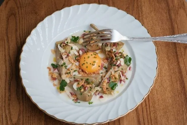 Carxofes brasejades al vi blanc amb vinagreta de pernil ibèric, rovell d'ou, ametlla i ceba cruixent