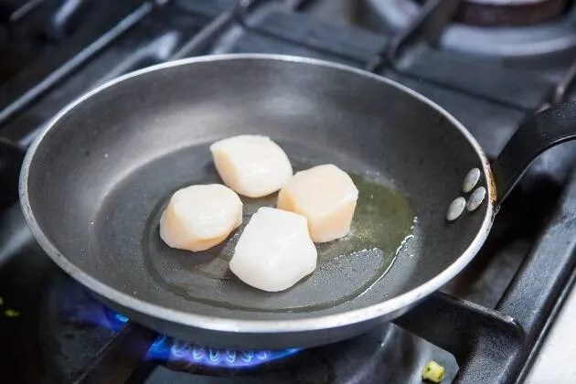 Vieires a la brasa amb crema de pèsols, coco i oli cítric