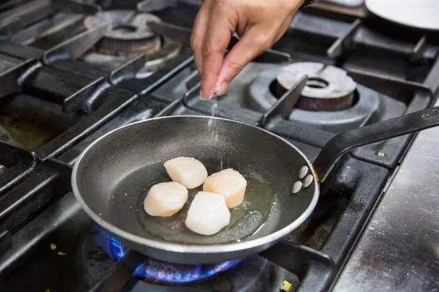 Vieires a la brasa amb crema de pèsols, coco i oli cítric