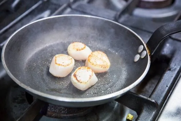 Vieires a la brasa amb crema de pèsols, coco i oli cítric