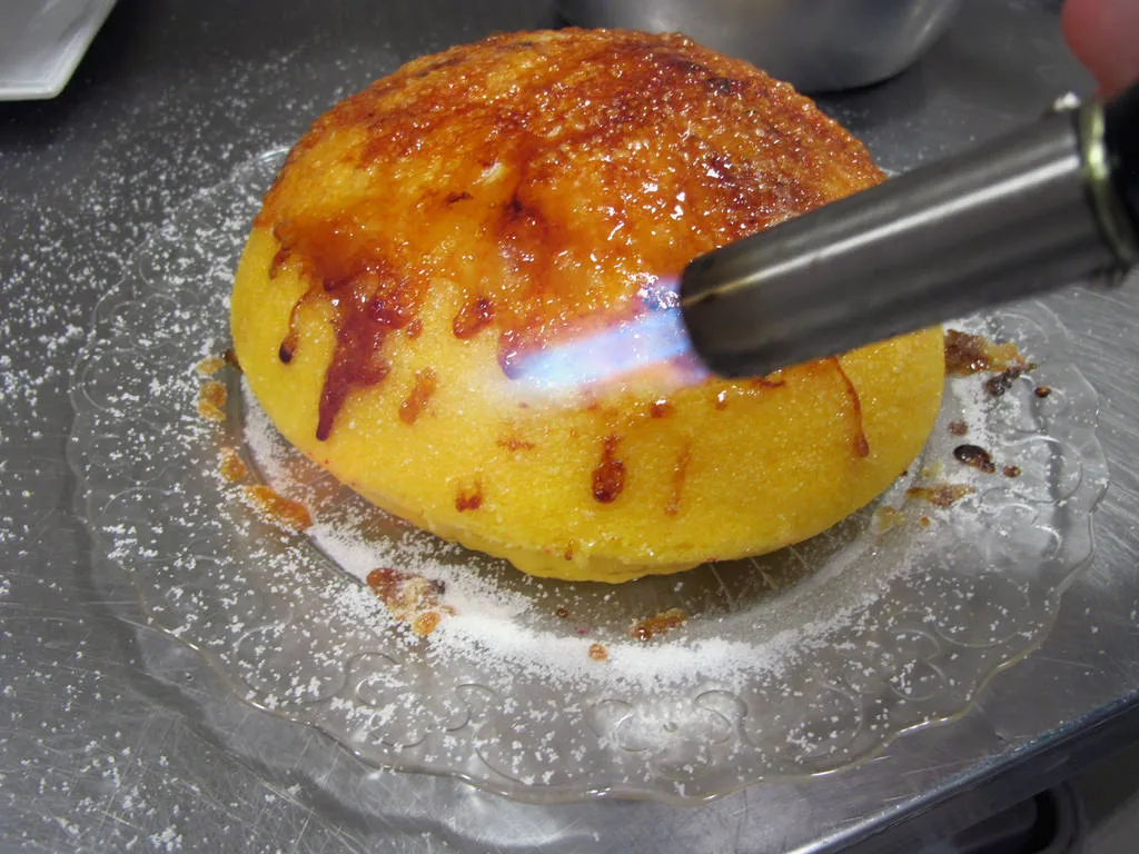 Espolvorear azúcar sobre la tarta ya desmoldada y quemar con soplete. Repetir esta técnica varias veces hasta crear una fina capa de caramelo crujiente