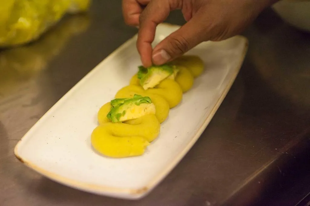 Colocar el aguacate sobre la masa de causa y seguidamente colocar el pulpo en láminas.