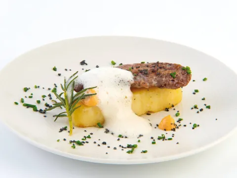 Cua de lagarto Joselito a la brasa de carbó d'alzina sobre lingot de patata natural confitada amb salsa brava obrera