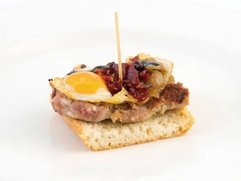 Botifarra de foie i poma esparracada amb ou de guatlla, ceba caramel·litzada, cruixent de pernil i reducció de Pedro Ximenes.