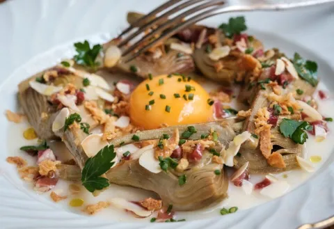 Carxofes brasejades al vi blanc amb vinagreta de pernil ibèric, rovell d'ou, ametlla i ceba cruixent