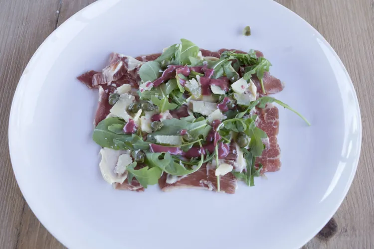 Carpaccio de presa ibérica con rúcula, parmesano y vinagreta de frutos rojos